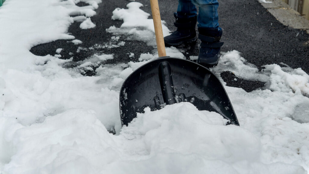 Boy clearing the backyard or walkway from snow after a snowstorm or blizzard